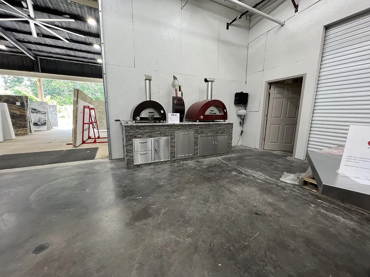 Two outdoor pizza ovens displayed on a stone kitchen island | Carpetland USA Granite & Flooring