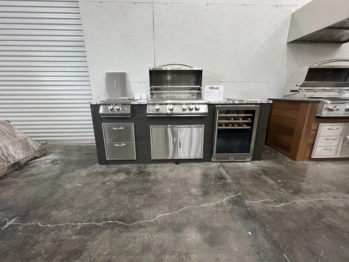 Outdoor kitchen setup with stainless steel grill, cabinets, and beverage cooler | Carpetland USA Granite & Flooring