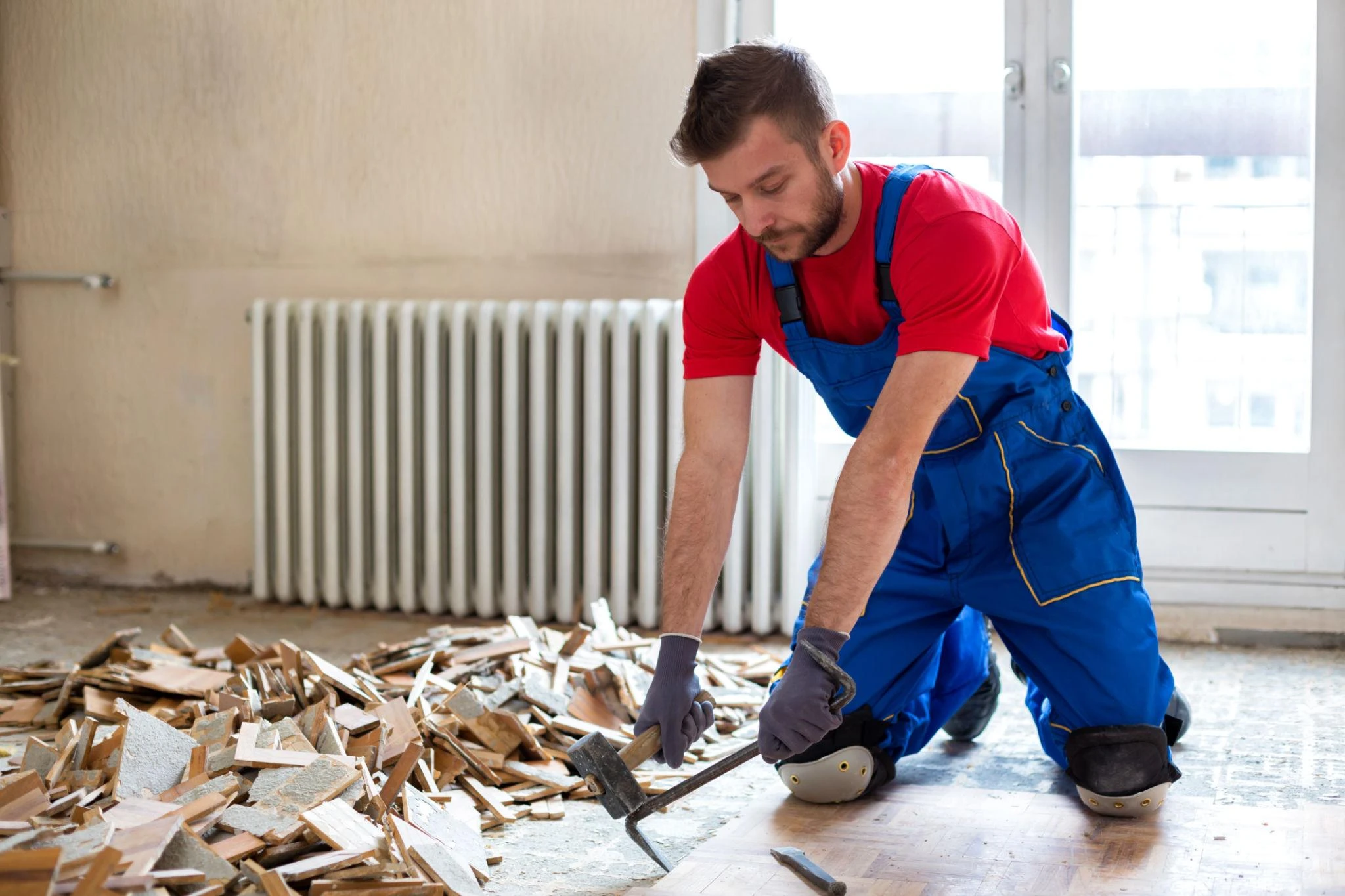 Worker removing old floor materials during a renovation | Carpetland USA Granite & Flooring