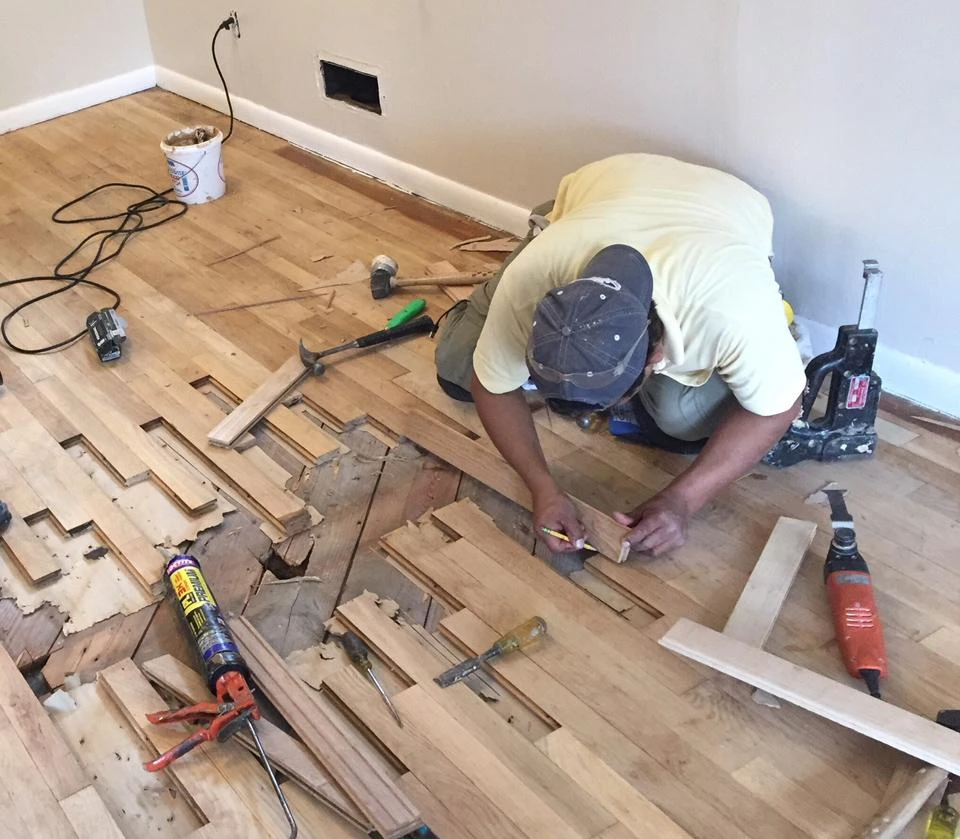 Flooring specialist replacing damaged wood floor boards during a repair project | Carpetland USA Granite & Flooring