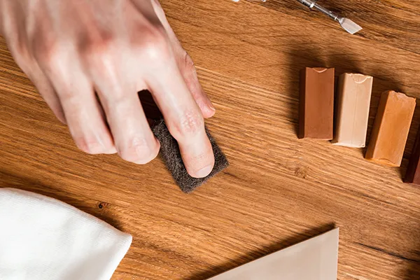 Worker repairing a scratch on a hardwood floor | Carpetland USA Granite & Flooring