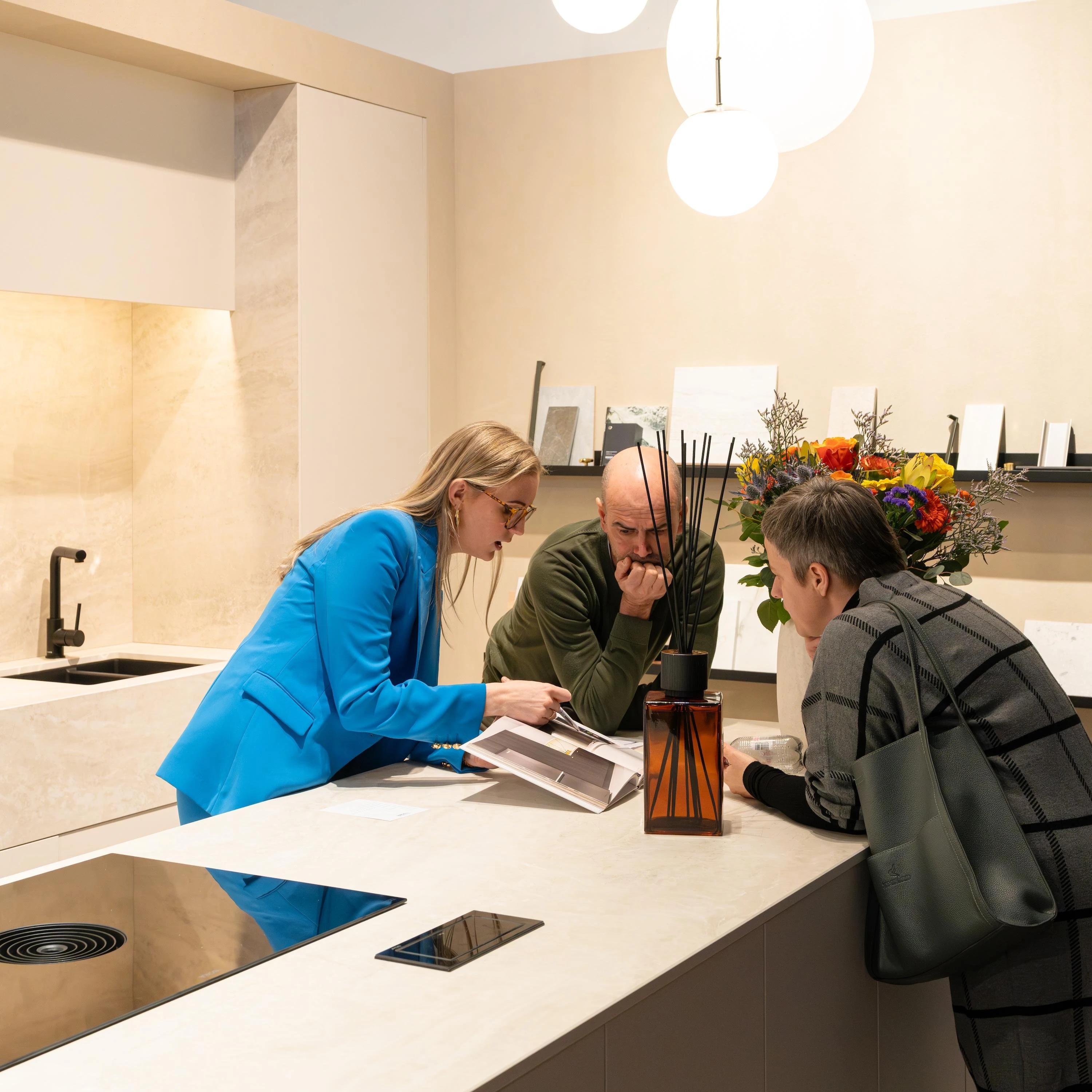 Kitchen designer in blue dress explaining material options to homeowners | Carpetland USA Granite & Flooring
