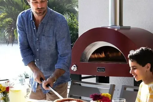 Man pull a pizza out of an outdoor pizza oven | Carpetland USA Granite & Flooring